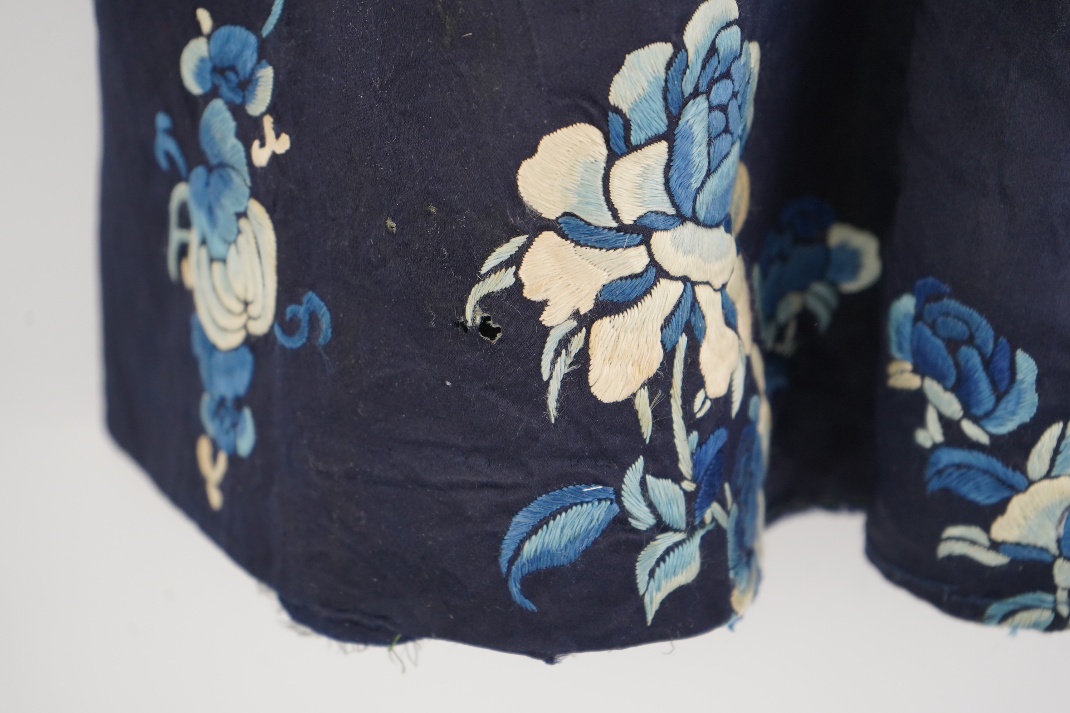 An early 20th century blue silk embroidered Chinese child’s robe, embroidered with bats and flower motifs, bordered with rows of silk braid. Condition - the original silk lining has been removed, it may benefit from bein